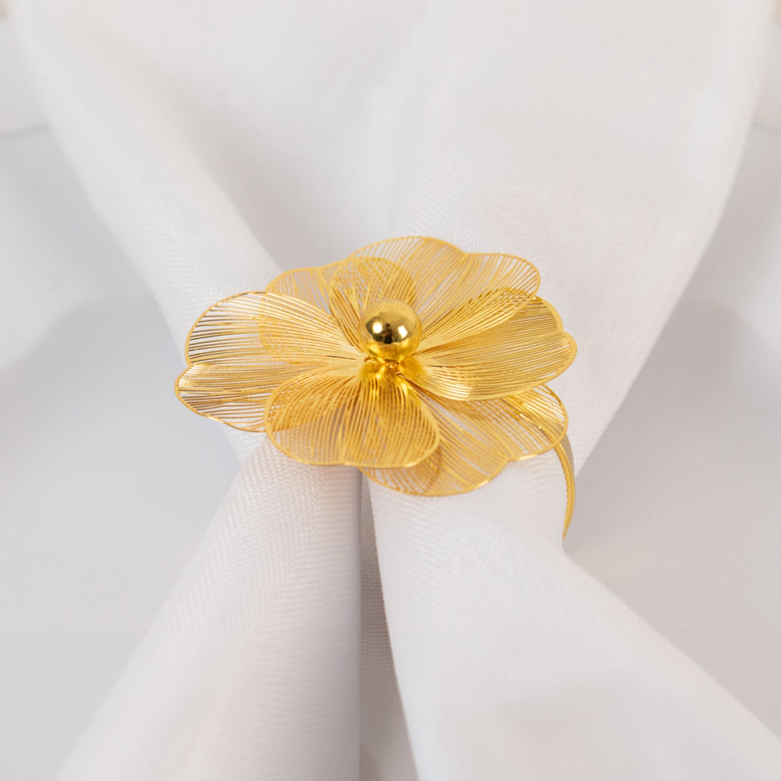 Gold floral napkin ring on a white napkin.