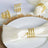 Gold napkin rings arranged on a white plate with a satin napkin.