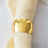 Gold hammered napkin ring on a light fabric napkin.