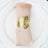 Gold leaf napkin ring on a beige napkin placed on a white plate.