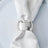Silver napkin ring on a white napkin atop a plate.