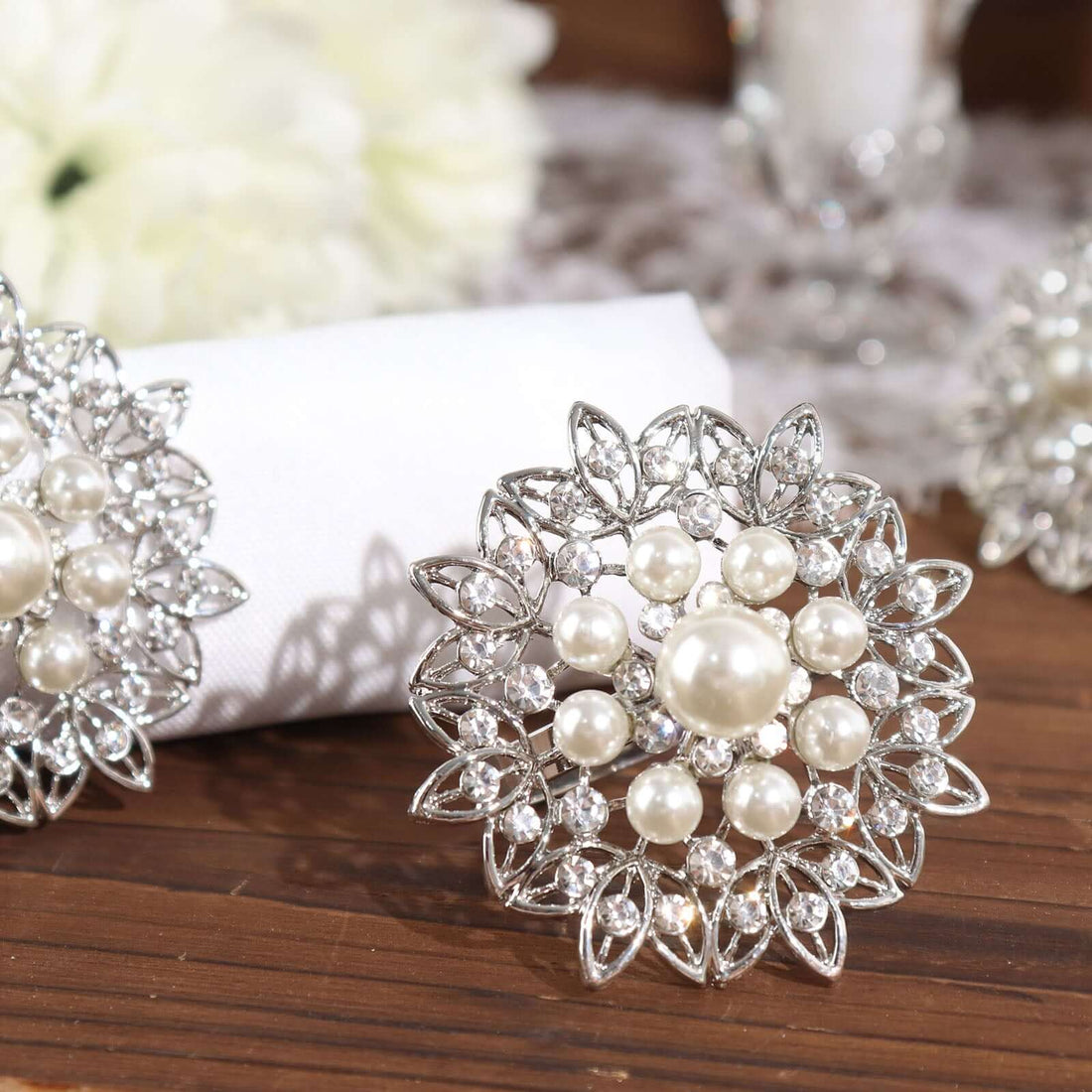Elegant silver and pearl floral brooch on a wooden surface.