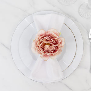 Elegant pink flower on a white plate setting with a napkin.