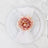 Elegant pink flower on a white plate setting with a napkin.