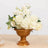 Gold vase with white floral arrangement on a wooden table.