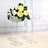 Clear crystal flower vases with yellow and white roses on a neutral background.