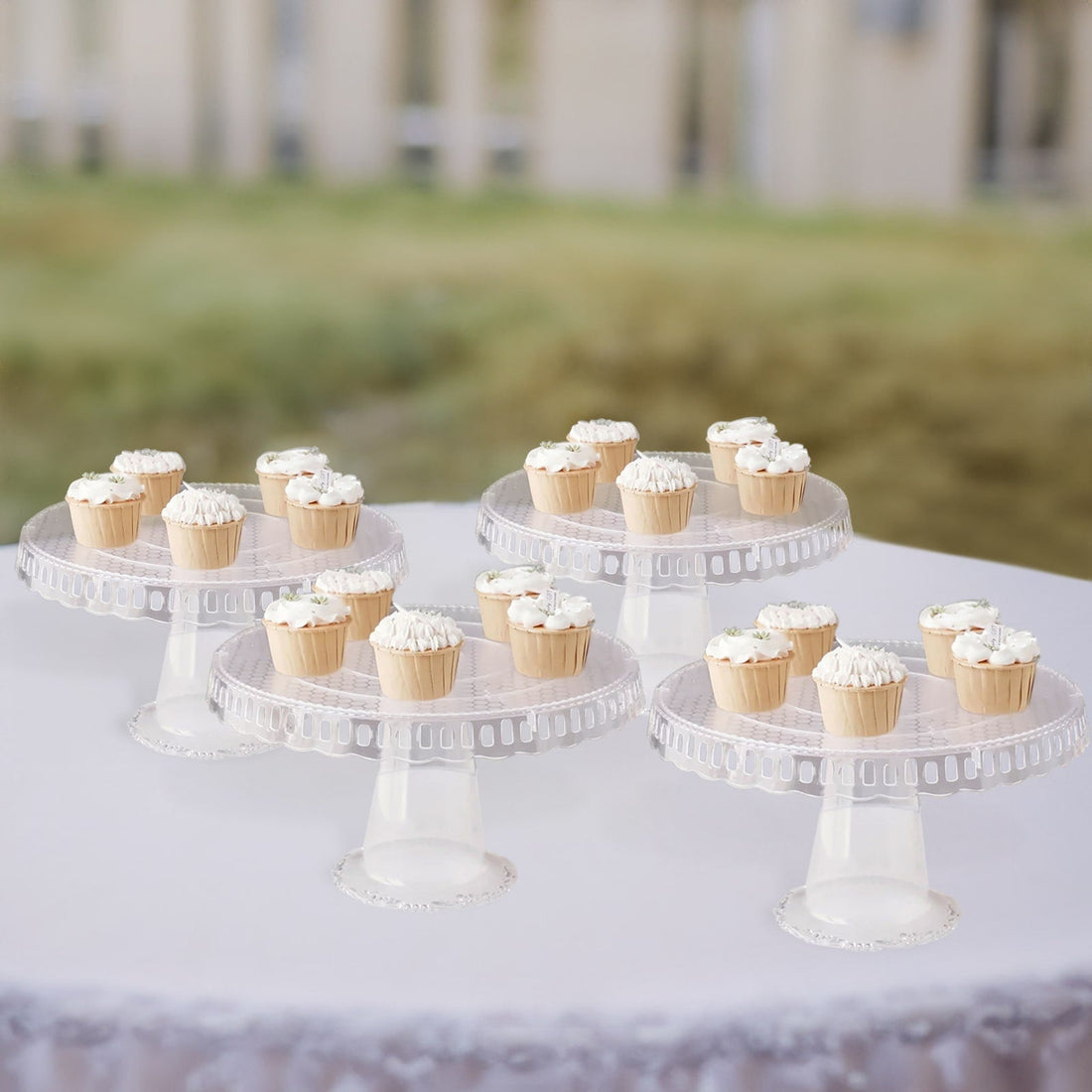 Clear plastic cupcake stands with frosted cupcakes on a table.