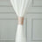 White curtain with a textured tieback against a neutral background.