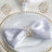 Elegant white satin napkin with crystal ring on a decorative plate.