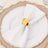 Gold napkin ring on a white plate with a folded napkin.