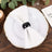 Elegant white napkin with black napkin ring on a decorative plate.