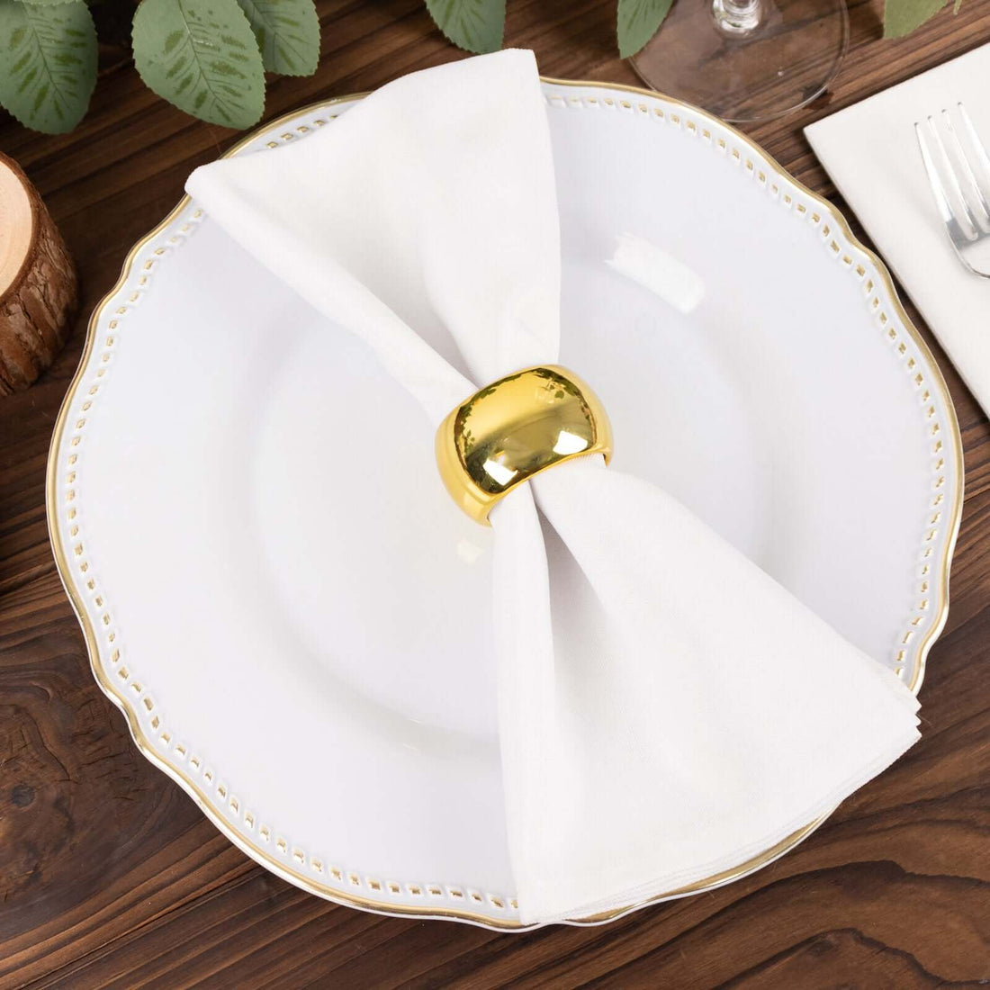 Gold napkin ring on a white plate with a folded napkin.