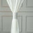 White curtain held with a silver decorative tieback.