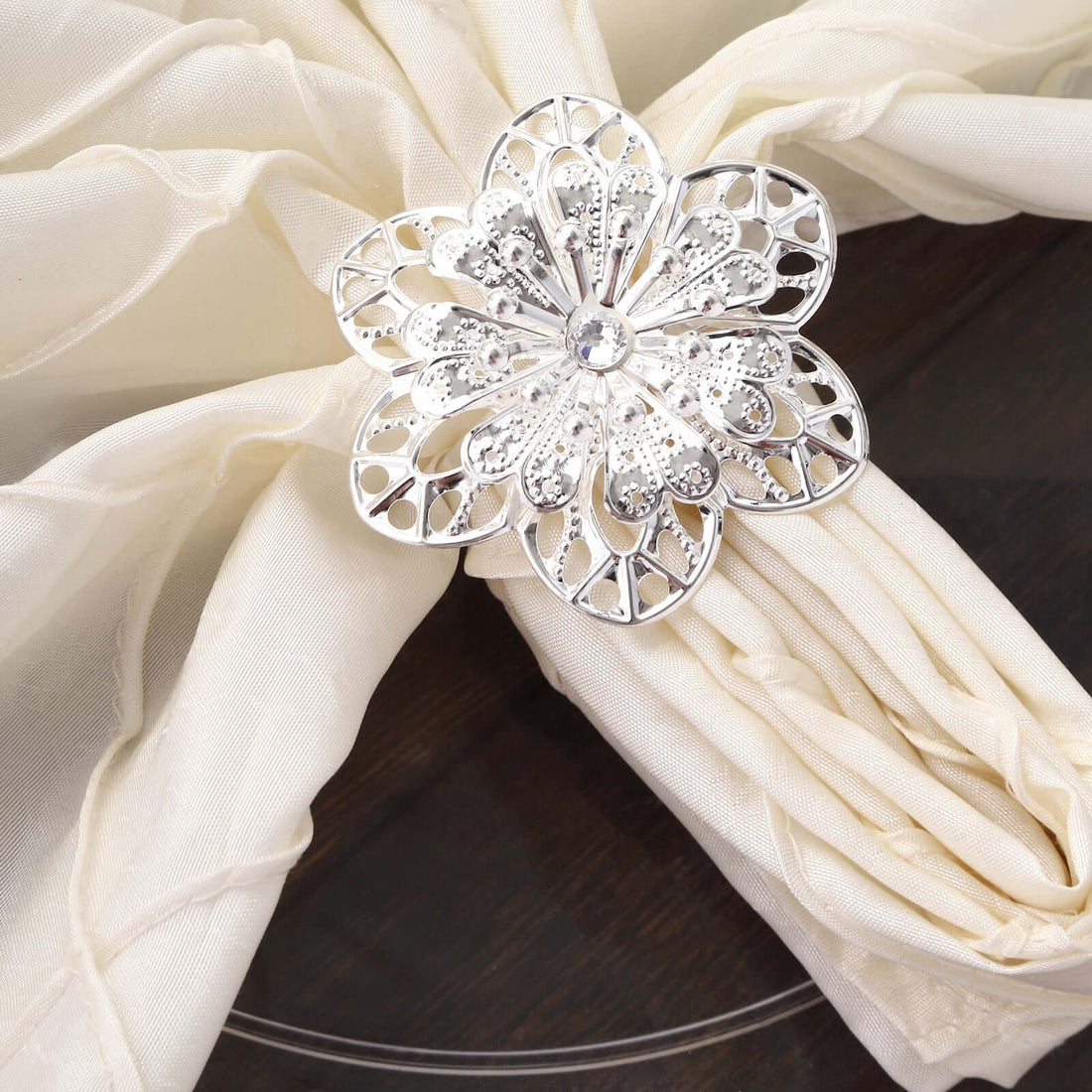 Silver flower napkin ring on a cream napkin.