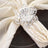 Silver flower napkin ring on a cream napkin.
