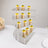 Clear acrylic dessert display stand with mini cakes arranged in tiers.