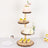 Wooden cake stand with cupcakes and a decorated cake on a plain white background.