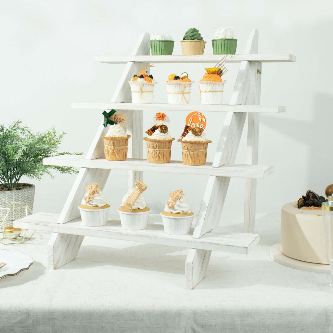 Colorful cupcakes displayed on a white wooden stand at a festive event.