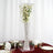 Crystal vase with flowers in a clear display box on a table setting.