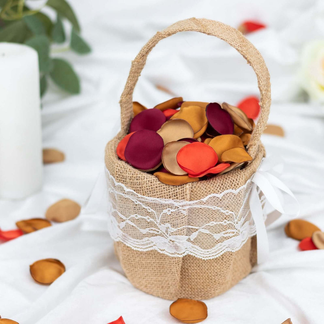 Burlap basket filled with colorful petals on a white surface.