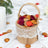 Burlap basket filled with colorful petals on a white surface.