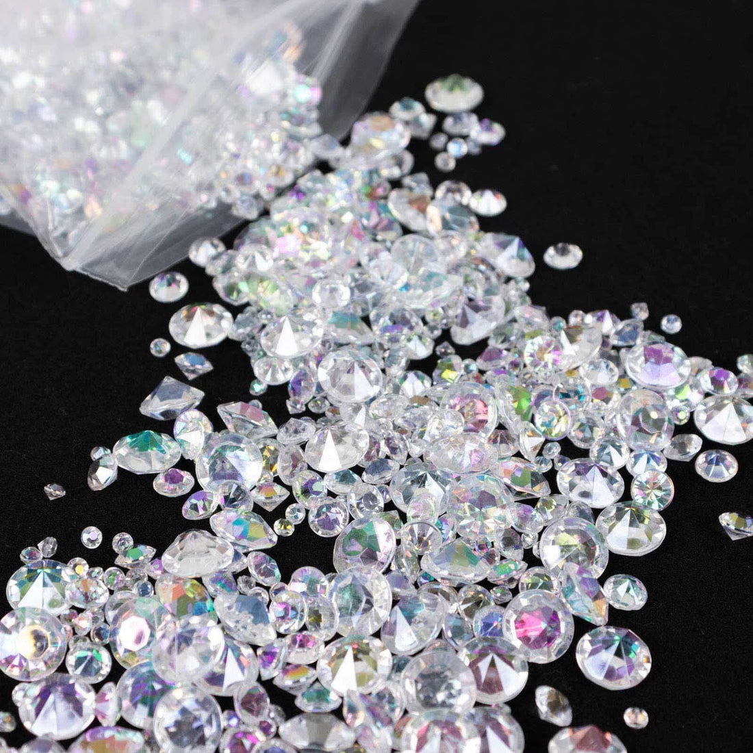 Mixed clear rhinestones scattered on a black surface.