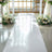 White aisle runner with floral arrangements on either side in a bright venue.