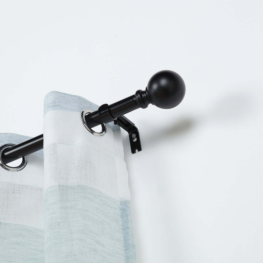 Curtain rod with striped curtain, featuring black hardware and rings.