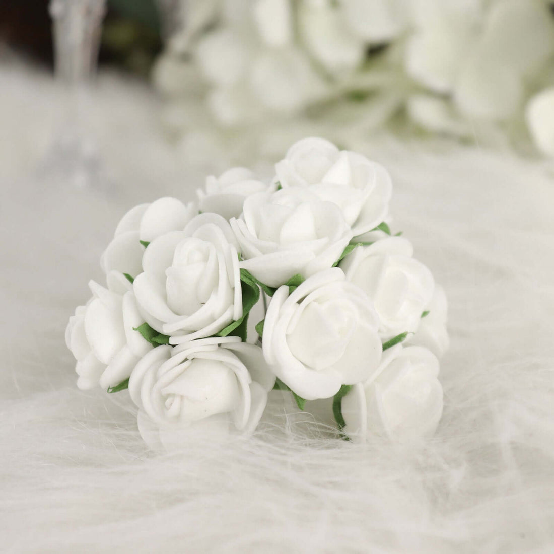 White artificial rose bouquet on soft white fabric.