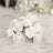 White artificial rose bouquet on soft white fabric.