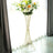 Gold wire flower stand with vibrant floral arrangement against a bright window.