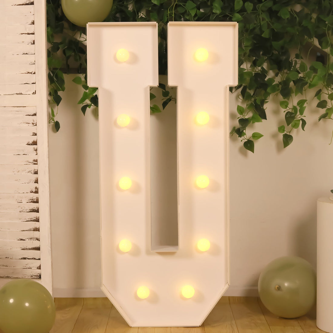 Decorative marquee letter 'U' with lights on a neutral background.