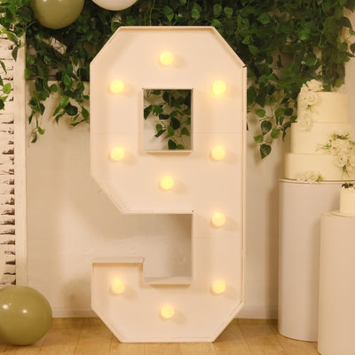 Large illuminated number 9 marquee sign with greenery and balloons