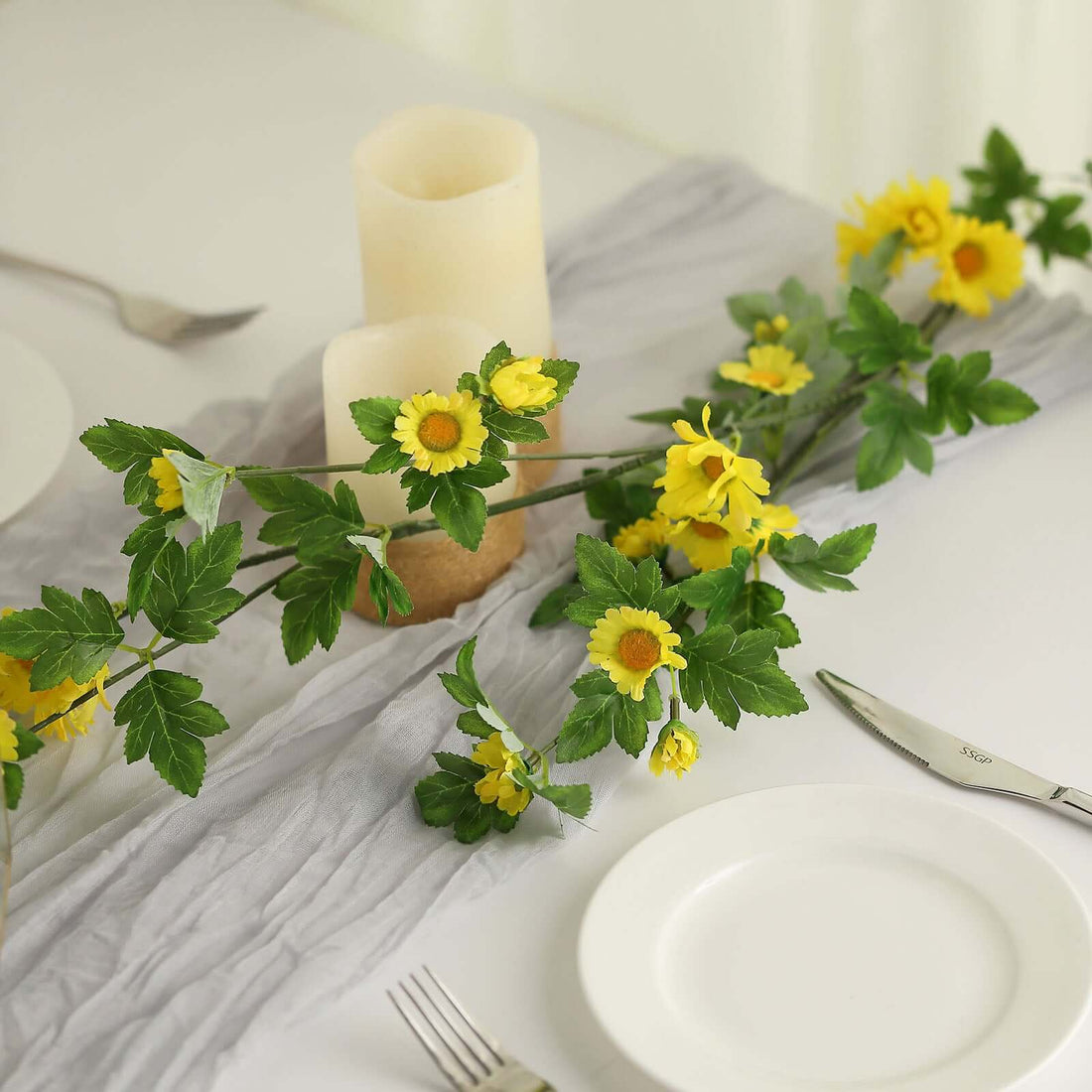 Yellow flowers and candles arranged on a table with plates and utensils.