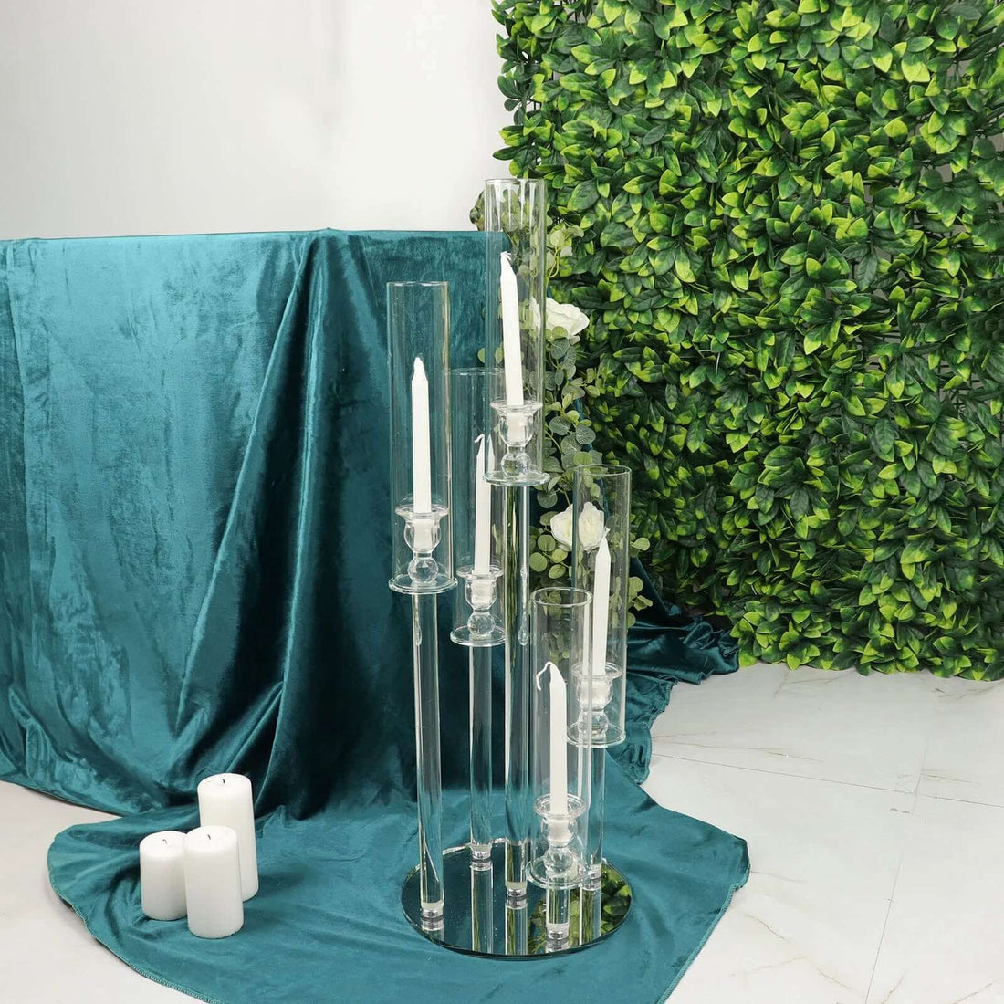 Elegant glass candle holders with white candles on a teal tablecloth.