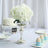 White hydrangea floral centerpiece in a silver vase on a wedding table setting.