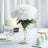 White hydrangea bouquet in a silver vase on a table setting.