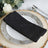 Black napkin elegantly arranged on a decorative plate with a rustic wooden base.