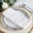 White napkin elegantly folded on a decorative plate with rustic wooden charger.