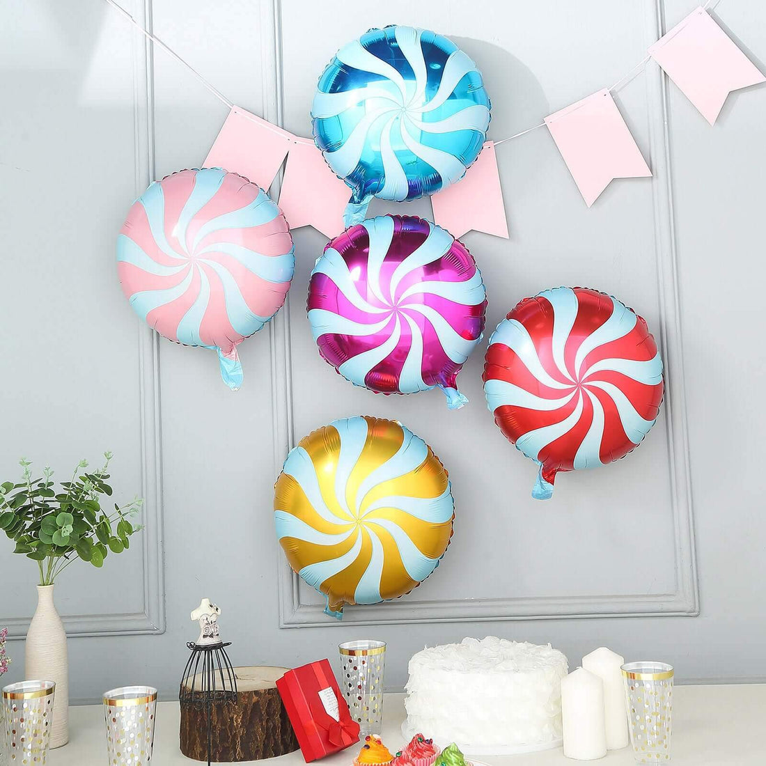 Colorful swirl balloons in a festive setting with decorations and a cake.