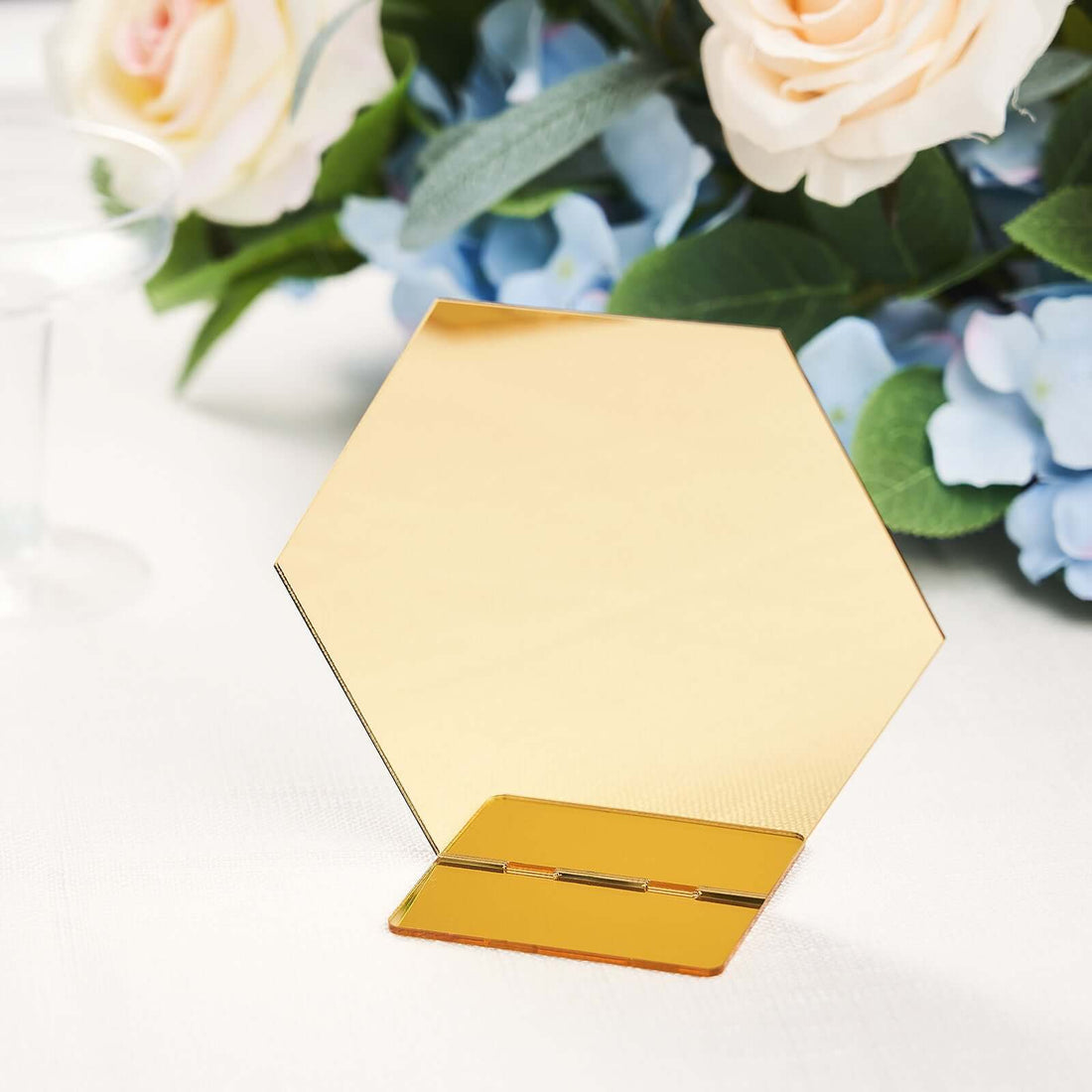 Gold hexagon mirror stand with floral backdrop.