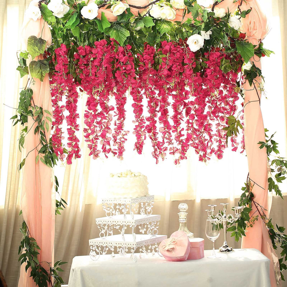 Wedding decoration with pink flowers and a cake table setup.