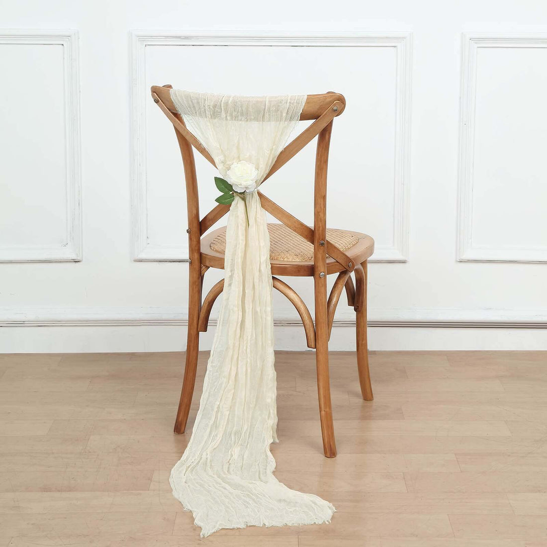 Elegant cream chair sash with flower detail tied on a wooden chair.
