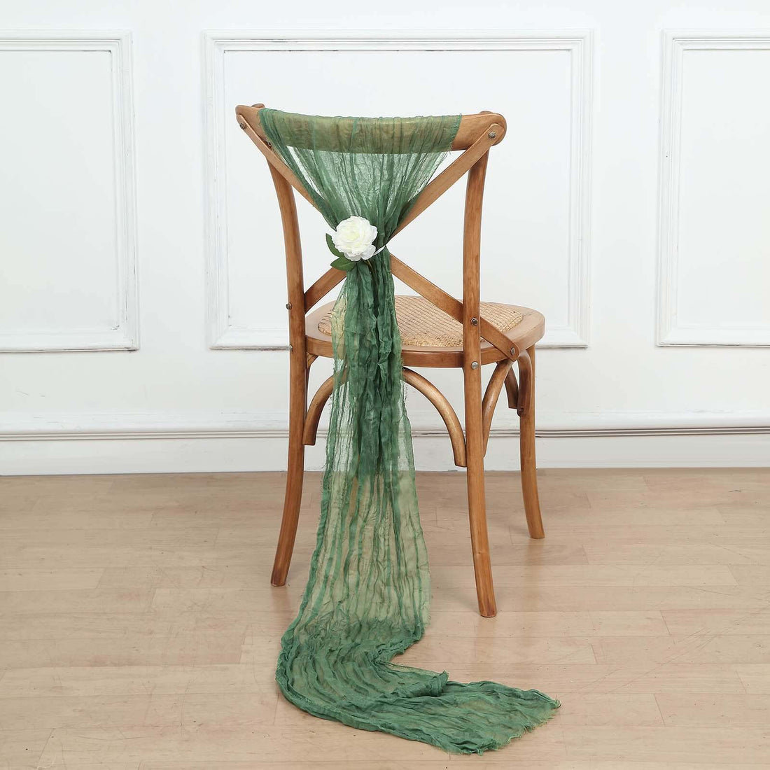 Green scarf draped on a wooden chair with a white flower accent.