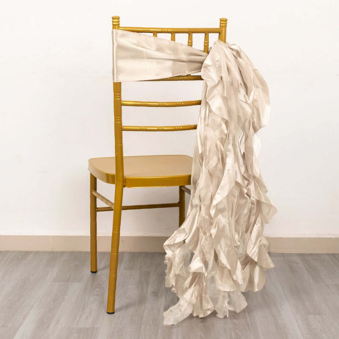 Gold chiavari chair with ruffled satin sash draped over the back.
