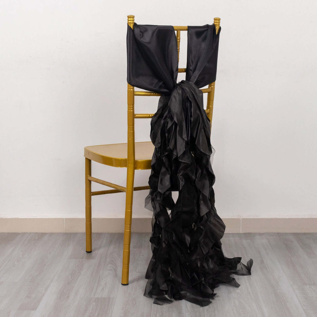 Black chair sash with ruffled design draping over a gold chair.
