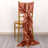Satin chair sash in rust color with ruffles draping down a gold chair