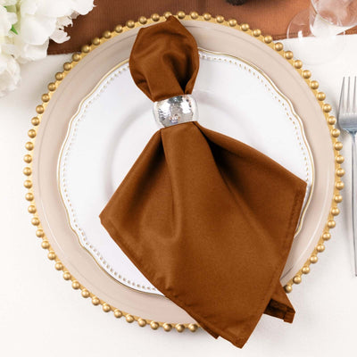 Brown napkin with silver napkin ring on elegant plate setting.