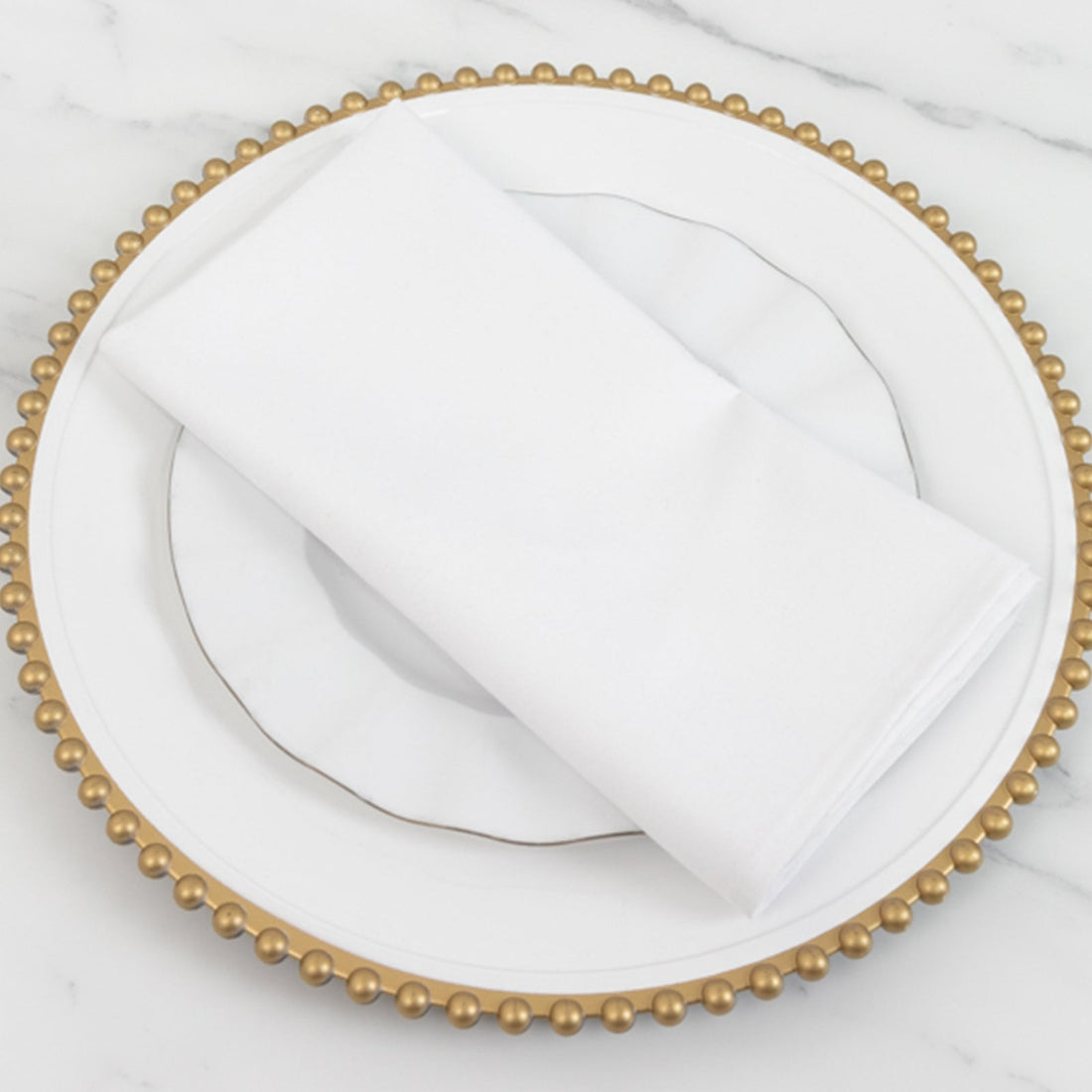 White napkin on an elegant gold beaded plate.