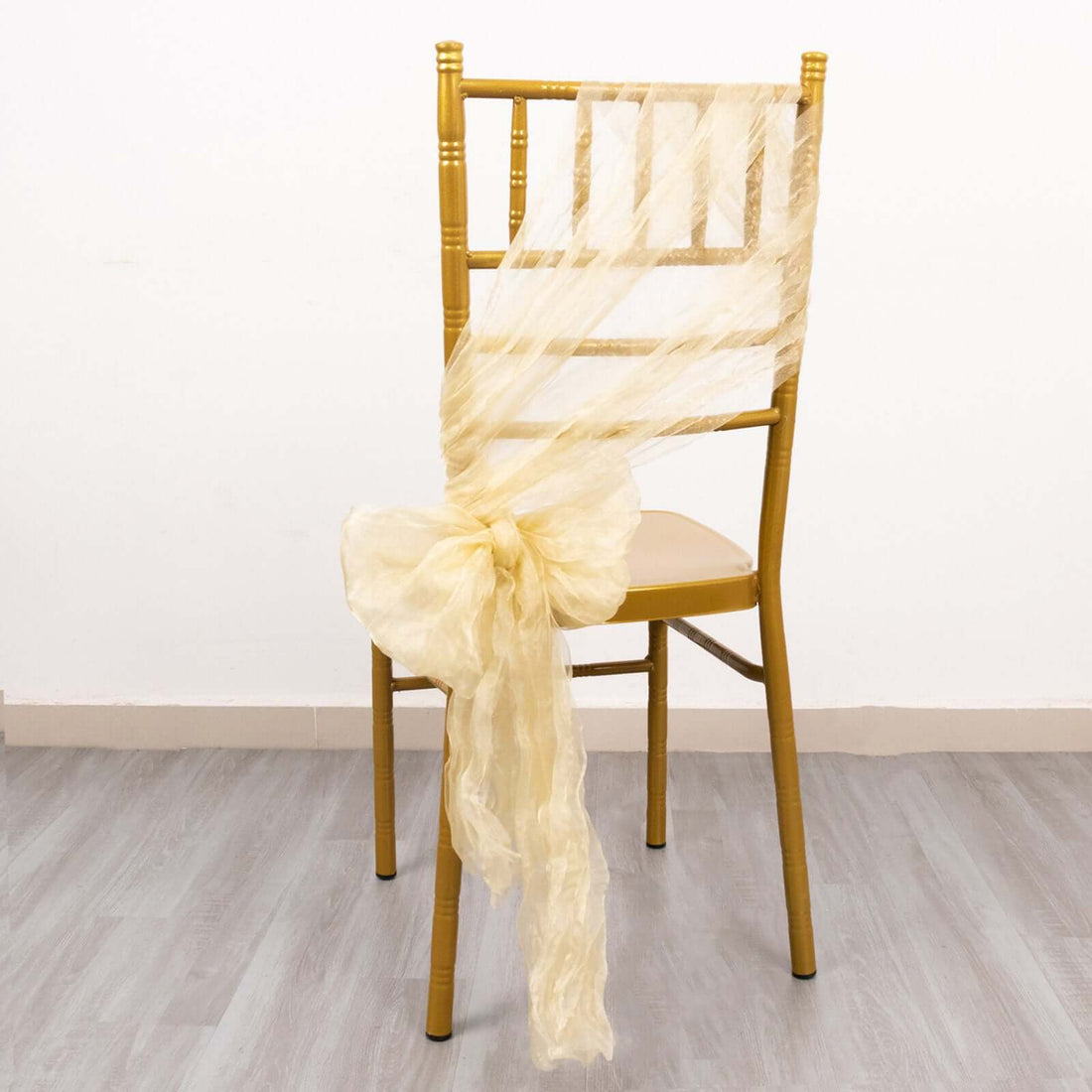 Gold chiavari chair with cream organza sash tied in a bow.